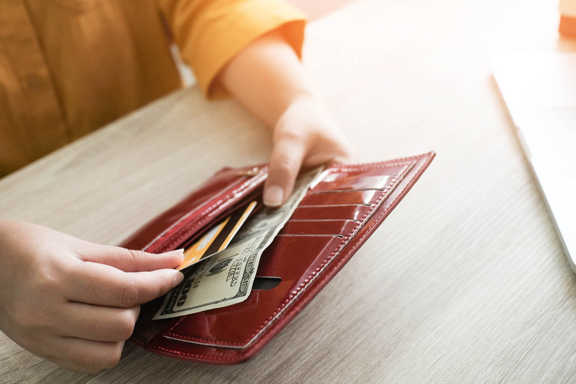 woman taking credit card and cash from red wallet