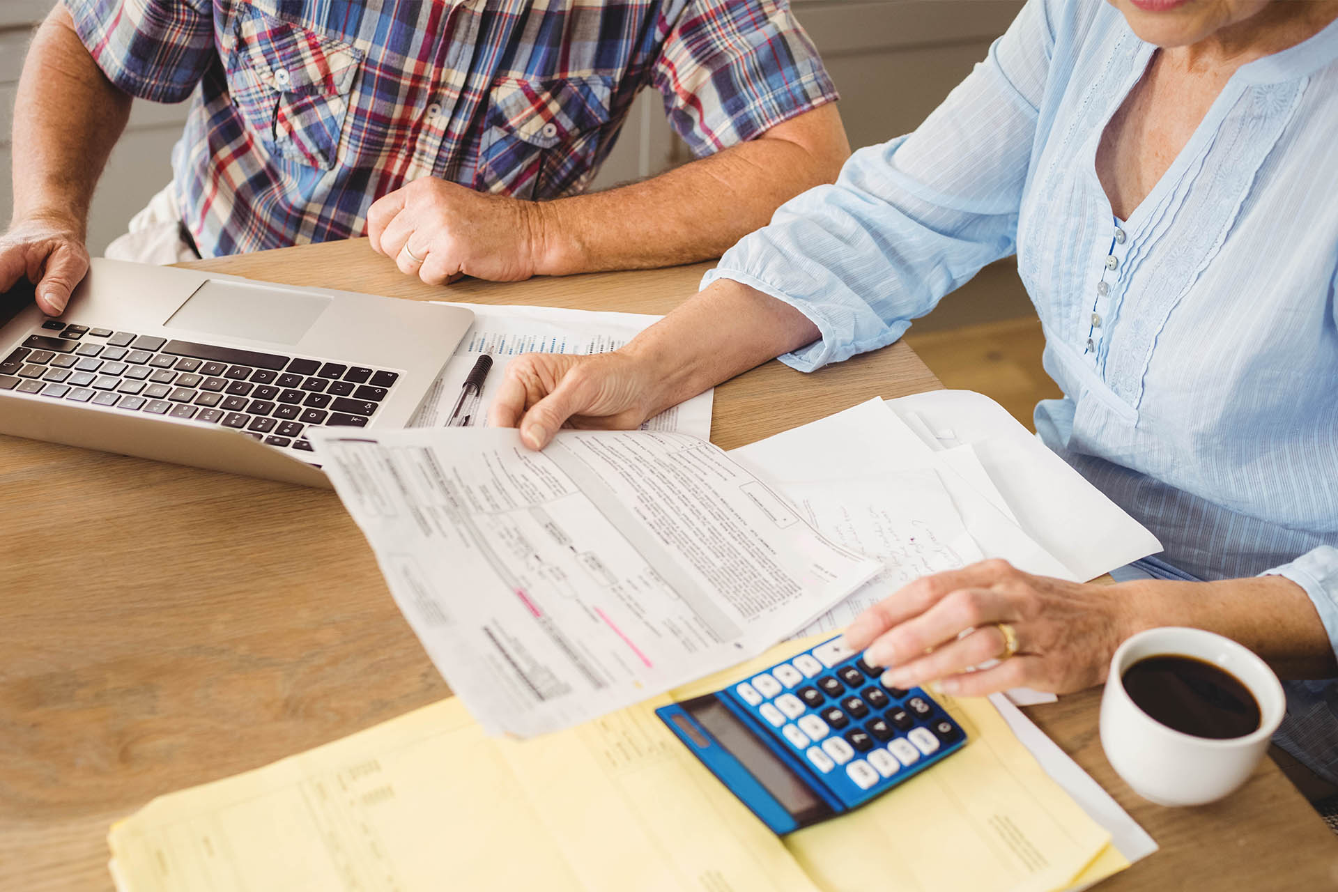 mature couple reviewing financial documents with calculator and computer at table